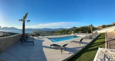 a swimming pool with chairs and a view of the ocean at Résidence du Château d'eau in Porticcio
