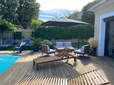 a patio with chairs and an umbrella next to a pool at Villa 2 chambres piscine in Cauro
