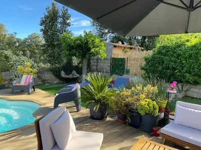 a patio with chairs and plants and an umbrella at Villa 2 chambres piscine in Cauro