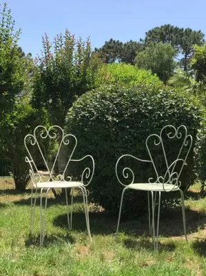 two wrought iron chairs sitting in the grass at Villa Pieds dans l eau in Porto-Vecchio