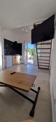 a living room with a table and a kitchen at Appartement a 5min de la plage in Penta-di-Casinca