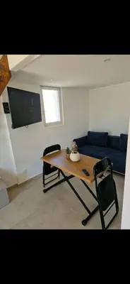 a living room with a table and a blue couch at Appartement a 5min de la plage in Penta-di-Casinca