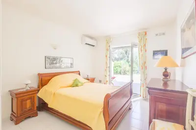 a bedroom with a bed with a yellow bedspread at Palmeria - Maison climatisée accès direct plage in Canale-di-Verde