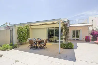 a patio with a table and chairs in a backyard at Palmeria - Maison climatisée accès direct plage in Canale-di-Verde