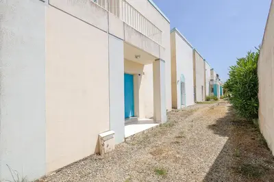 an alley between two buildings with blue doors at Palmeria - Maison climatisée accès direct plage in Canale-di-Verde