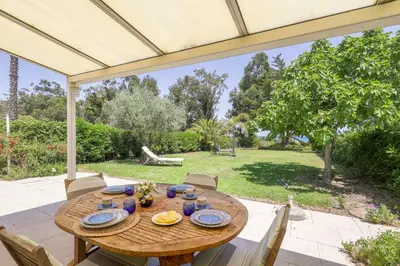 a wooden table and chairs on a patio at Palmeria - Maison climatisée accès direct plage in Canale-di-Verde