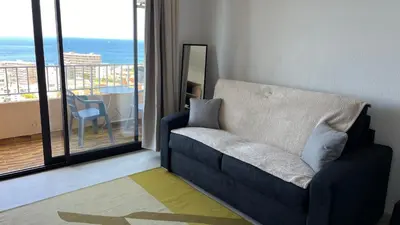 a blue couch in a living room with a balcony at Le plein soleil in Ajaccio