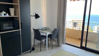 a room with a table and chairs and a balcony at Le plein soleil in Ajaccio
