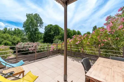 an outdoor patio with a table and chairs and flowers at La Belle-Hélène - Proche plage, 30 min d'ajaccio in Albitreccia