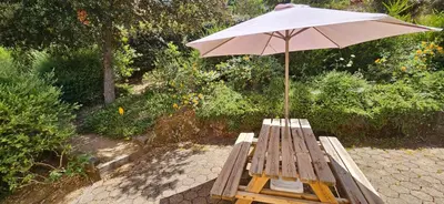 a wooden bench with an umbrella on a patio at T2 Résidence Dolce & Vita C4 vue mer et piscine in Propriano
