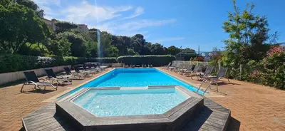 a swimming pool with chairs and a fountain at T2 Résidence Dolce & Vita C4 vue mer et piscine in Propriano