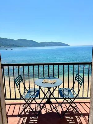 a table and chairs on a balcony overlooking the ocean at A 20min d AJACCIO, Grand studio 3 personnes - pieds dans l'eau - accès direct plage - vue mer exceptionnelle in Casaglione