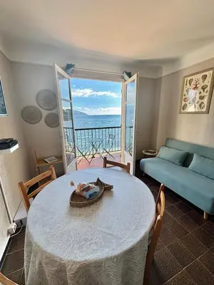 a living room with a table and a view of the ocean at A 20min d AJACCIO, Grand studio 3 personnes - pieds dans l'eau - accès direct plage - vue mer exceptionnelle in Casaglione