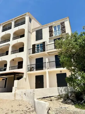 an apartment building with balconies on a beach at A 20min d AJACCIO, Grand studio 3 personnes - pieds dans l'eau - accès direct plage - vue mer exceptionnelle in Casaglione