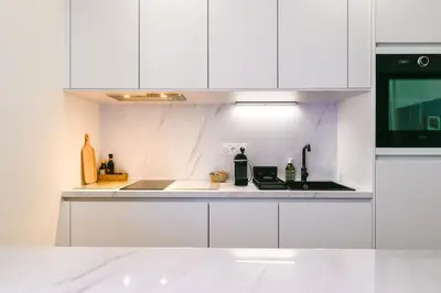 a white kitchen with white cabinets and a sink at Studio Cosy à Ajaccio in Ajaccio