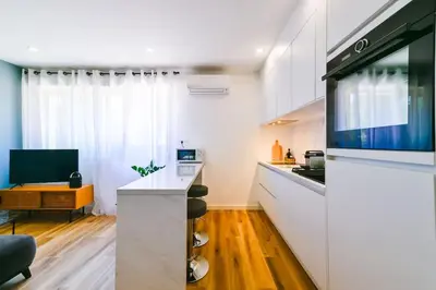 a kitchen with white cabinets and a living room at Studio Cosy à Ajaccio in Ajaccio