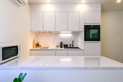 a white kitchen with white cabinets and a microwave at Studio Cosy à Ajaccio in Ajaccio