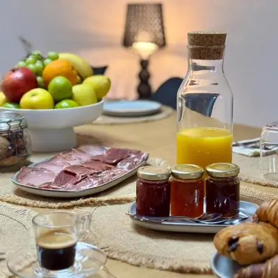 a table with a plate of meat and a bottle of juice at Bella Vita in Calenzana