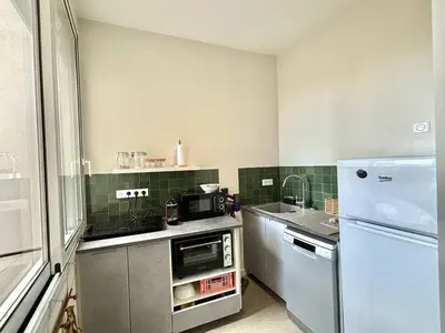 a small kitchen with a refrigerator and a sink at Appartement studio cours napoleon Ajaccio in Ajaccio