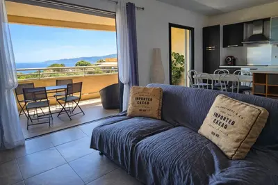 a blue couch in a living room with a balcony at T3 de standing Vigna Majo vue mer imprenable in Propriano