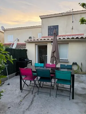 a table with chairs and an umbrella in front of a house at Maison a la plage in Poggio-Mezzana