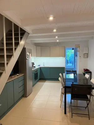 a kitchen with green cabinets and a table and a staircase at Maison a la plage in Poggio-Mezzana