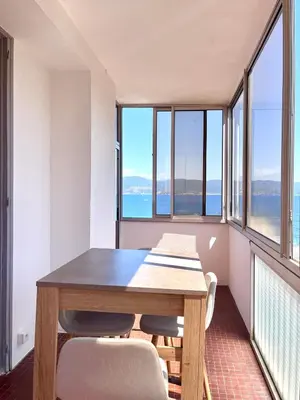 a dining room with a table and chairs and windows at Front de mer Beau T3 climatisé Balcon Parking Ajaccio in Ajaccio