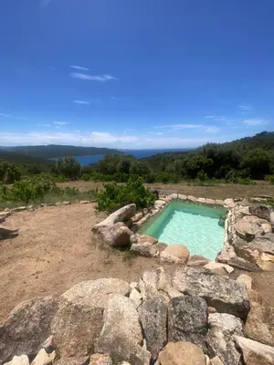 a swimming pool in a field with rocks at A Malgrana - Tente lodge hébergement insolite in Coti-Chiavari
