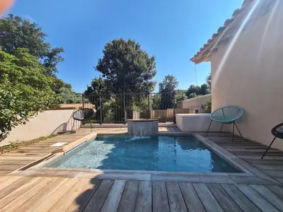 a small pool on a wooden deck with two chairs at Perla Di Macchia in Bonifacio
