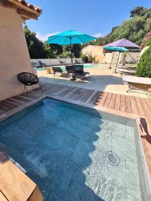 a swimming pool with a table and chairs and an umbrella at Perla Di Macchia in Bonifacio