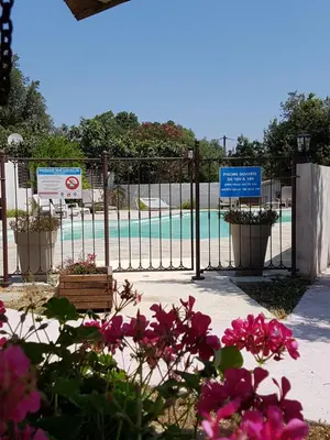 a gate with pink flowers in front of a pool at Perla Di Macchia in Bonifacio