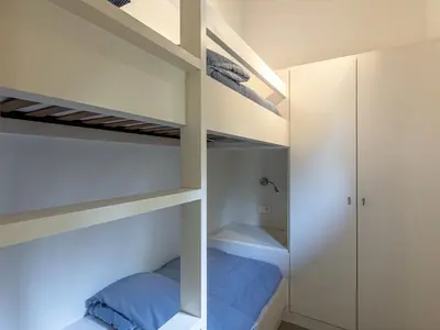 a bedroom with white bunk beds and a closet at Apartment Le Trois du Petit Sperone by Interhome in Bonifacio