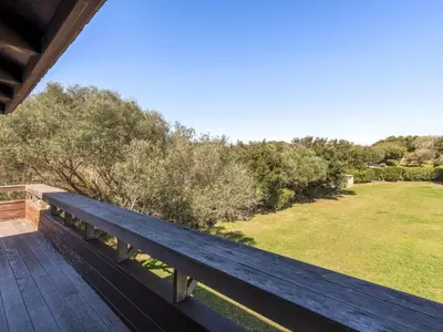 a wooden bench sitting on the deck of a house at Apartment Le Trois du Petit Sperone by Interhome in Bonifacio