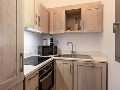 a small kitchen with wooden cabinets and a sink at Apartment Le Trois du Petit Sperone by Interhome in Bonifacio
