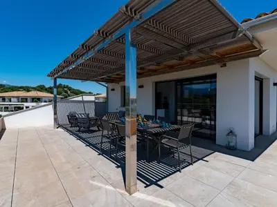 a pergola on a patio with a table and chairs at Apartment Domaine d'Arca-1 by Interhome in Porto-Vecchio