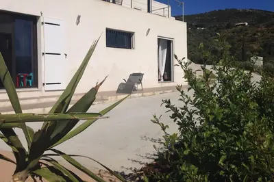 a white building with a chair in front of it at Rez de villa, vue panoramique mer et montagne ! in Vico