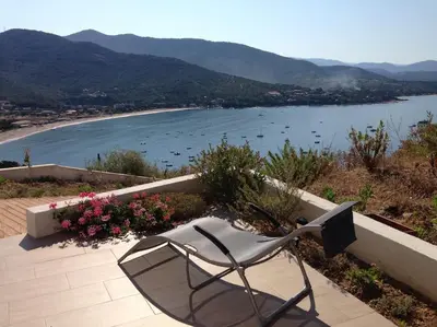 a chair sitting on a patio overlooking a beach at Rez de villa, vue panoramique mer et montagne ! in Vico