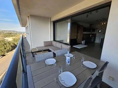 a balcony with a table and chairs and a couch at Studio Nautilus N7 proche centre-ville Porto-vecchio in Porto-Vecchio