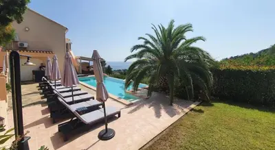 a swimming pool with chairs and umbrellas next to a house at Villa avec vue sur la mer à Sari-Solenzara, piscine privée in Sari Solenzara
