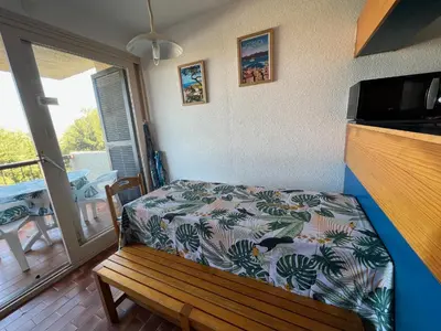 a bedroom with a bench and a balcony with a table at Bella Vista 42, T2 vue mer piscine Porticcio in Porticcio