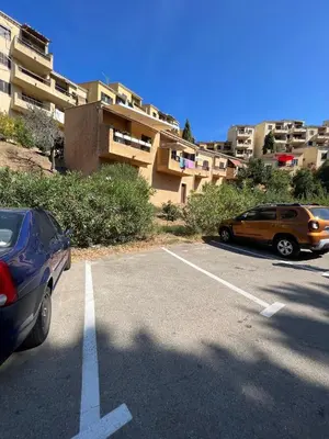 two cars parked in a parking lot in front of a building at Bella Vista 42, T2 vue mer piscine Porticcio in Porticcio