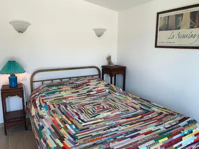 a bed with a colorful quilt on it in a bedroom at Chambre indépendante dans villa bord de mer in Vico