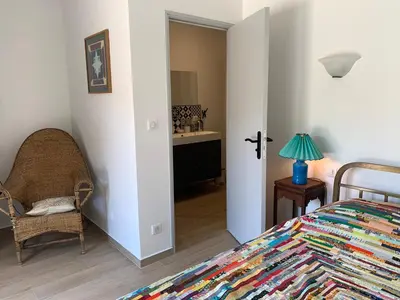a bedroom with a bed and a chair and a sink at Chambre indépendante dans villa bord de mer in Vico