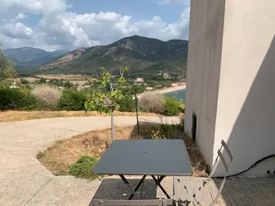 a table and a chair sitting next to a building at Chambre indépendante dans villa bord de mer in Vico