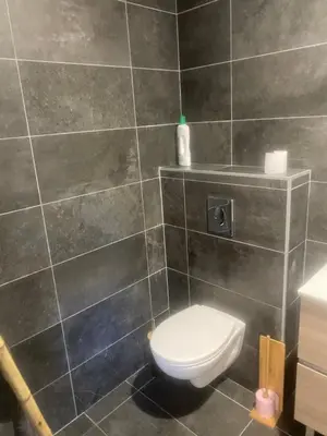 a bathroom with a toilet and a tiled wall at Casa Missia in Porto-Vecchio