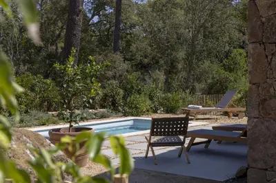 a pool with two chairs and a table and a bench at Hameau de Petripini in Sotta