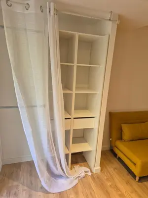 a book shelf with a curtain in a room at Studio dans résidence calme in Porto-Vecchio