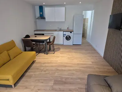 a living room with a couch and a table and a kitchen at Studio dans résidence calme in Porto-Vecchio