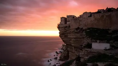 a castle on the side of a cliff near the ocean at Studio dans résidence calme in Porto-Vecchio