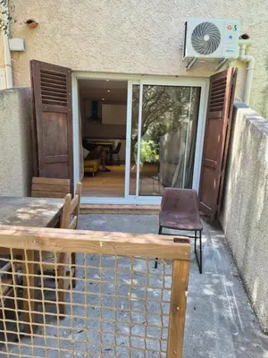 a wooden bench sitting in front of a house at Studio dans résidence calme in Porto-Vecchio